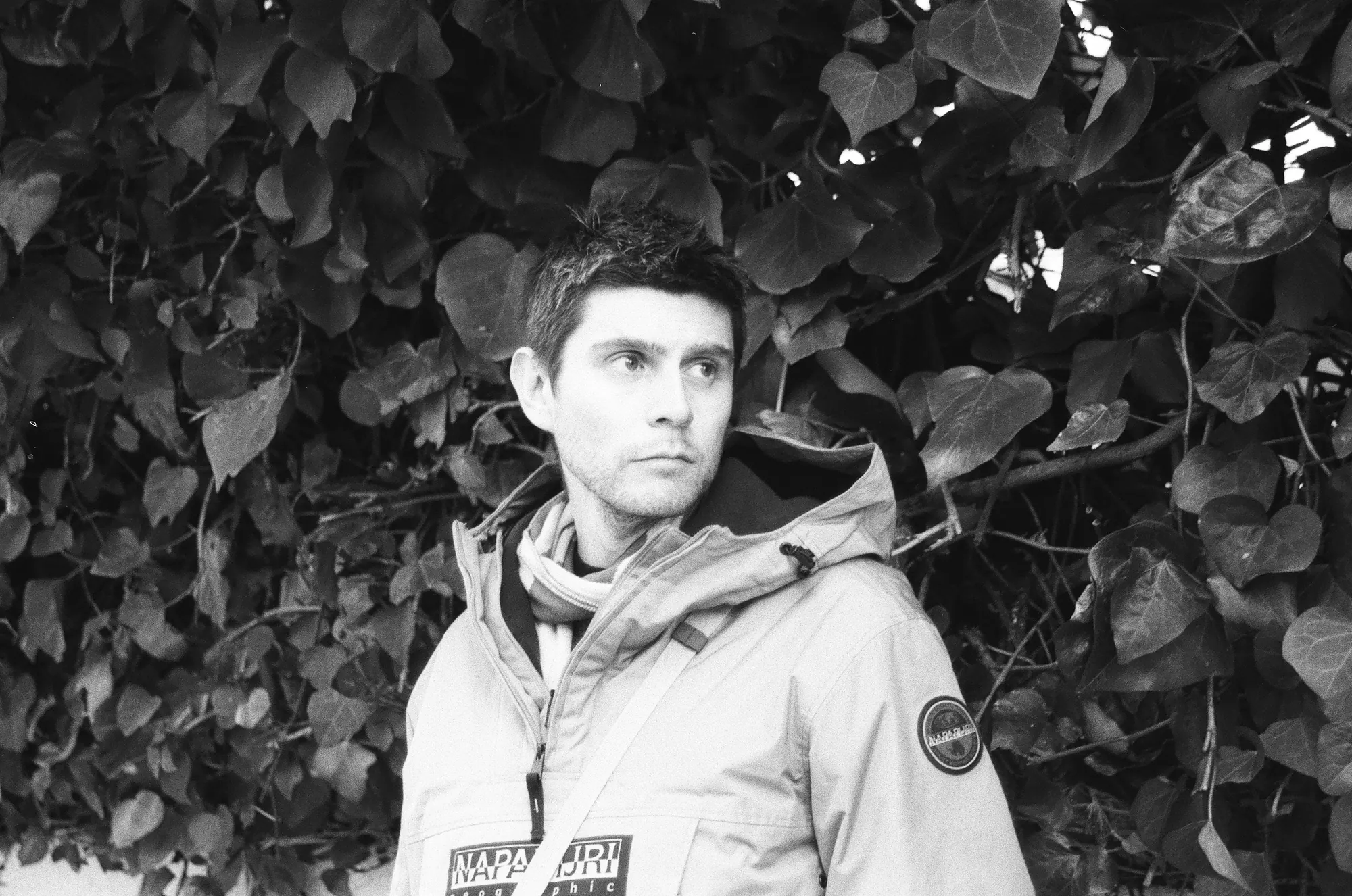 Pedro Espinosa, black-and-white portrait in front of ivy